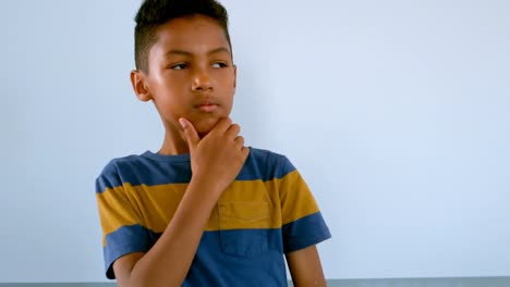 Young-African-American-boy-with-hand-on-chin-standing-against-whiteboard-in-classroom-4k
