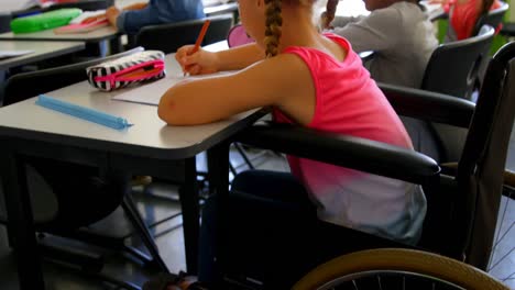 Disabled-Caucasian-schoolgirl-studying-at-desk-in-classroom-at-school-4k