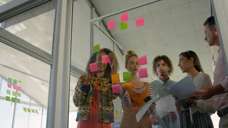 Low-angle-view-of-mixed-race-business-executives-intercating-each-others-about--sticky-notes-in-mode