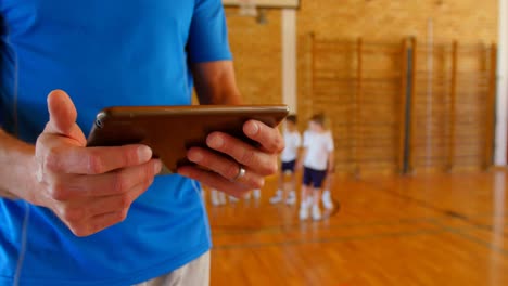 Entrenador-De-Baloncesto-Usando-Tableta-Digital-En-La-Cancha-De-Baloncesto-De-La-Escuela-4k