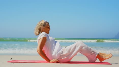 Side-view-of-active-senior-Caucasian-woman-performing-yoga-on-the-beach-4k