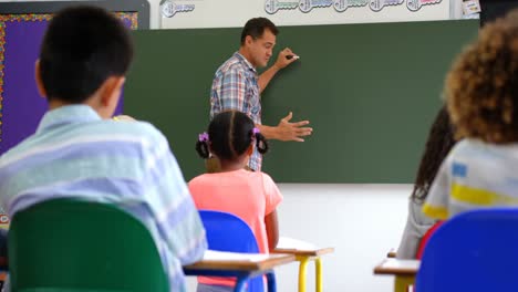 Seitenansicht-Eines-Kaukasischen-Männlichen-Lehrers,-Der-Schulkinder-Auf-Dem-Whiteboard-Im-Klassenzimmer-Unterrichtet-4k