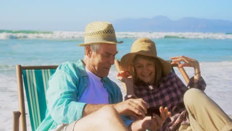 Front-view-of-active-senior-Caucasian-couple-taking-selfie-with-mobile-phone-on-the-beach-4k