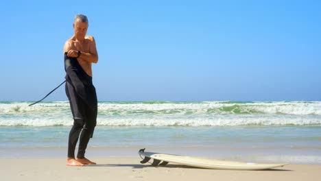 Side-view-of-active-senior-Caucasian-male-surfer-wearing-wet-suit-on-the-beach-4k