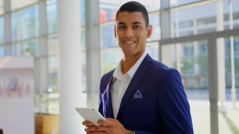 Mixed-race-businessman-holding-a-digital-tablet-in-the-lobby-at-office-4k