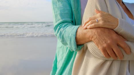 Mid-section-of-active-senior-Caucasian-couple-embracing-each-other-on-the-beach-4k