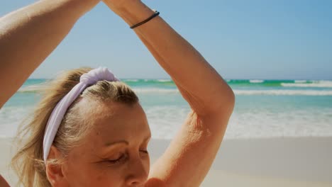Front-view-of-active-senior-Caucasian-woman-performing-yoga-on-the-beach-4k
