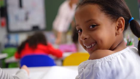Rückansicht-Eines-Glücklichen-Kaukasischen-Schulmädchens,-Das-Im-Klassenzimmer-In-Die-Kamera-Schaut,-4K