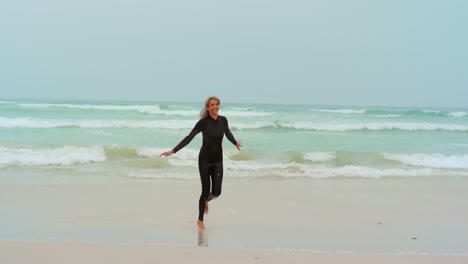 Front-view-of-active-senior-African-American-female-surfer-running-on-the-beach-4k