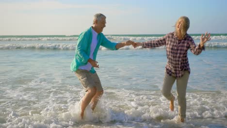 Seitenansicht-Eines-Aktiven-älteren-Kaukasischen-Paares,-Das-Gemeinsam-Am-Strand-4k-Tanzt