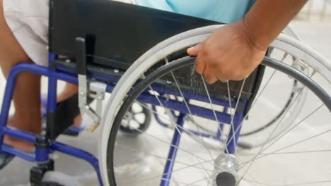 Nahaufnahme-Eines-Behinderten-Aktiven-älteren-Afroamerikanischen-Mannes,-Der-Seinen-Rollstuhl-Auf-Der-Promenade-Bewegt,-4k