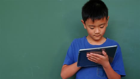 Front-view-of-Asian-schoolboy-studying-with-digital-tablet-in-classroom-at-school-4k