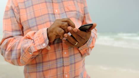 Mittelteil-Eines-Aktiven-älteren-Afroamerikanischen-Mannes,-Der-Sein-Mobiltelefon-Am-Strand-Nutzt,-4K