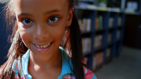 Front-view-of-happy-African-American-schoolgirl-standing-in-library-at-school-4k