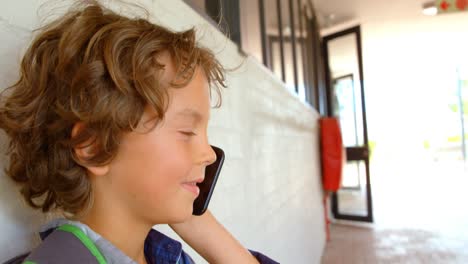 Side-view-of-Caucasian-schoolboy-talking-on-mobile-phone-in-school-corridor-4k