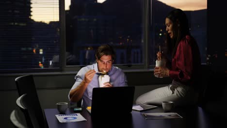 Front-view-of-young-Caucasian-office-executives-eating-food-at-desk-in-modern-office-4k
