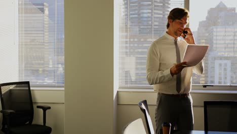 Front-view-of-young-Caucasian-male-executive-talking-on-mobile-phone-in-a-modern-office-4k