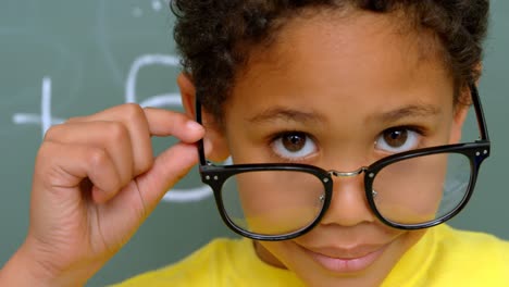Close-up-of-African-American-schoolboy-looking-over-spectacle-in-classroom-at-school-4k-