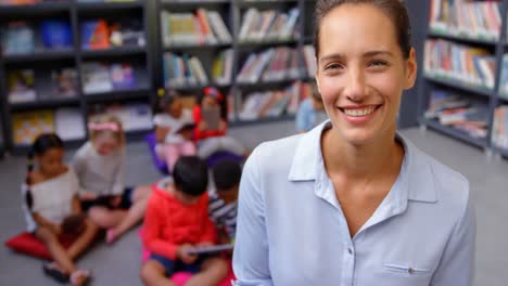 Front-view-of-happy-Caucasian-female-teacher-standing-in-the-school-library-4k