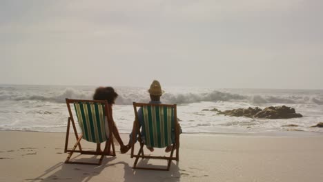 Rückansicht-Eines-Afroamerikanischen-Paares,-Das-Sich-Gemeinsam-Auf-Einer-Sonnenliege-Am-Strand-Entspannt,-4k