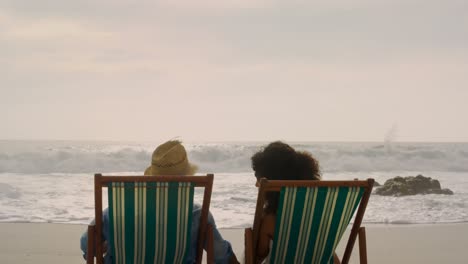 Rückansicht-Eines-Afroamerikanischen-Paares,-Das-Sich-Gemeinsam-Auf-Einer-Sonnenliege-Am-Strand-Entspannt,-4k