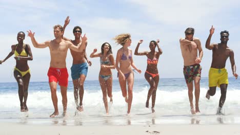 Front-view-of-mixed-race-friends-running-together-on-the-beach-4k