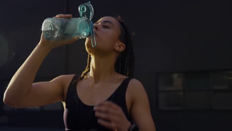 Vista-Frontal-De-Una-Joven-Afroamericana-Bebiendo-Agua-En-La-Ciudad-4k