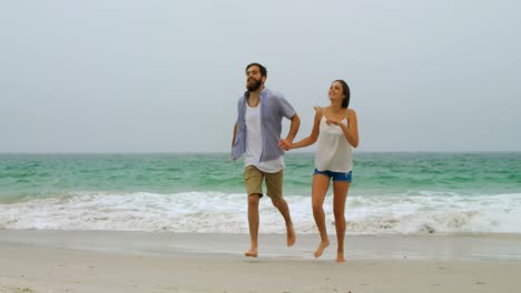 Front-view-of-Caucasian-couple-running-with-hand-in-hand-on-the-beach-4k