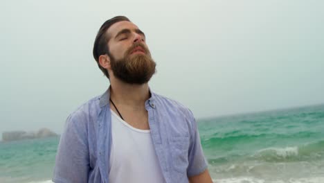 Front-view-of-Caucasian-man-standing-with-eye-closed-on-the-beach-4k