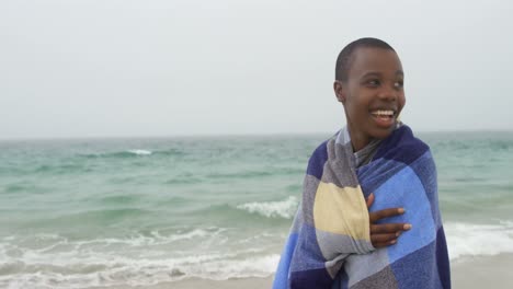 -Front-view-of-African-american-woman-wrapped-in-blanket-on-the-beach-4k