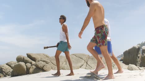 Side-view-of-mixed-race-male-friends-carrying-ice-box-on-the-beach-4k