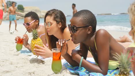 Side-view-of-mixed-race-female-friends-drinking-cocktail-drinks-on-the-beach-4k