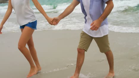 Front-view-of-Caucasian-couple-walking-with-hand-in-hand-on-the-beach-4k