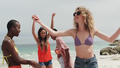 Group-of-mixed-race-female-friends-dancing-together-on-the-beach-4k