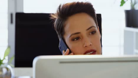 Front-view-of-Caucasian-Businesswoman-talking-on-mobile-phone-at-desk-in-a-modern-office-4k