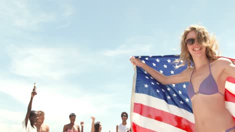 Vista-Frontal-De-Una-Mujer-Caucásica-Bailando-Con-Bandera-Americana-En-La-Playa-4k