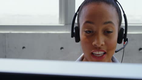 Vista-Frontal-De-Una-Mujer-De-Negocios-Afroamericana-Hablando-Con-Auriculares-En-El-Escritorio-De-Una-Oficina-Moderna-4k