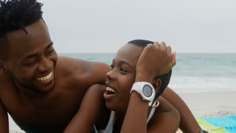 Front-view-of-African-american-couple-relaxing-on-the-beach-4k
