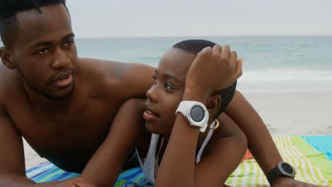 Front-view-of-African-american-couple-relaxing-on-the-beach-4k