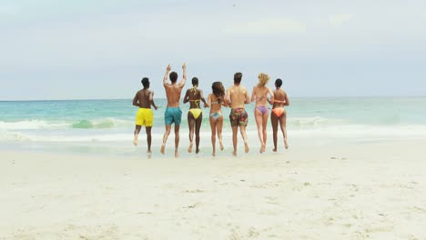 Group-of-mixed-race-friends-running-together-on-the-beach-4k