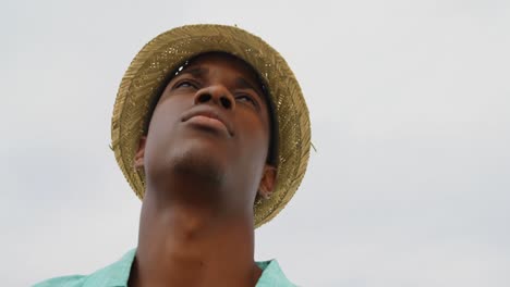 Low-Angle-Ansicht-Eines-Afroamerikanischen-Mannes-Mit-Hut,-Der-Am-Strand-Steht-4k