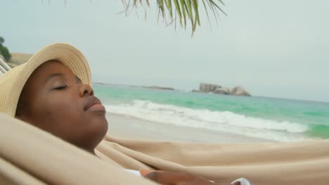 Side-view-of-African-american-woman-sleeping-in-a-hammock-on-the-beach-4k