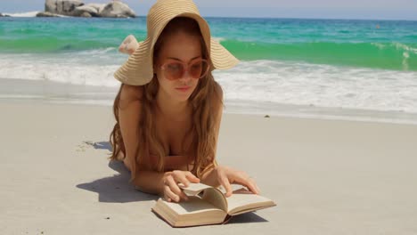 Vorderansicht-Einer-Kaukasischen-Frau-Mit-Hut,-Die-Am-Strand-Ein-Buch-Liest,-4k