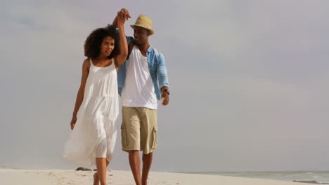 Front-view-of-African-american-couple-walking-hand-in-hand-on-the-beach-4k