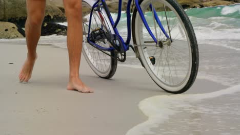 Low-section-of-man-walking-with-bicycle-on-the-beach-4k