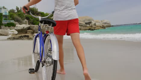 Rear-view-of-Caucasian-man-walking-with-bicycle-on-the-beach-4k