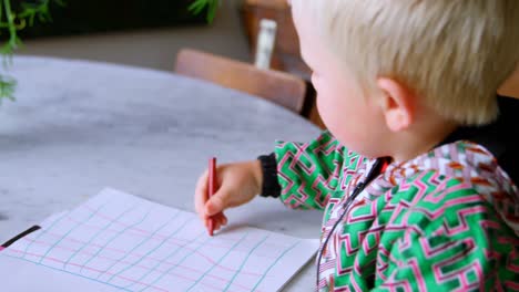 Boy-drawing-with-coloured-crayon-on-paper-at-home-4k