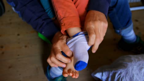 Father-helping-his-son-to-put-socks-on-in-bedroom-at-home-4k