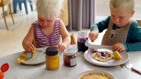 Siblings-eating-pancakes-at-dining-table-4k