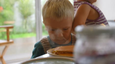 Siblings-looking-at-pancakes-on-dining-table-4k